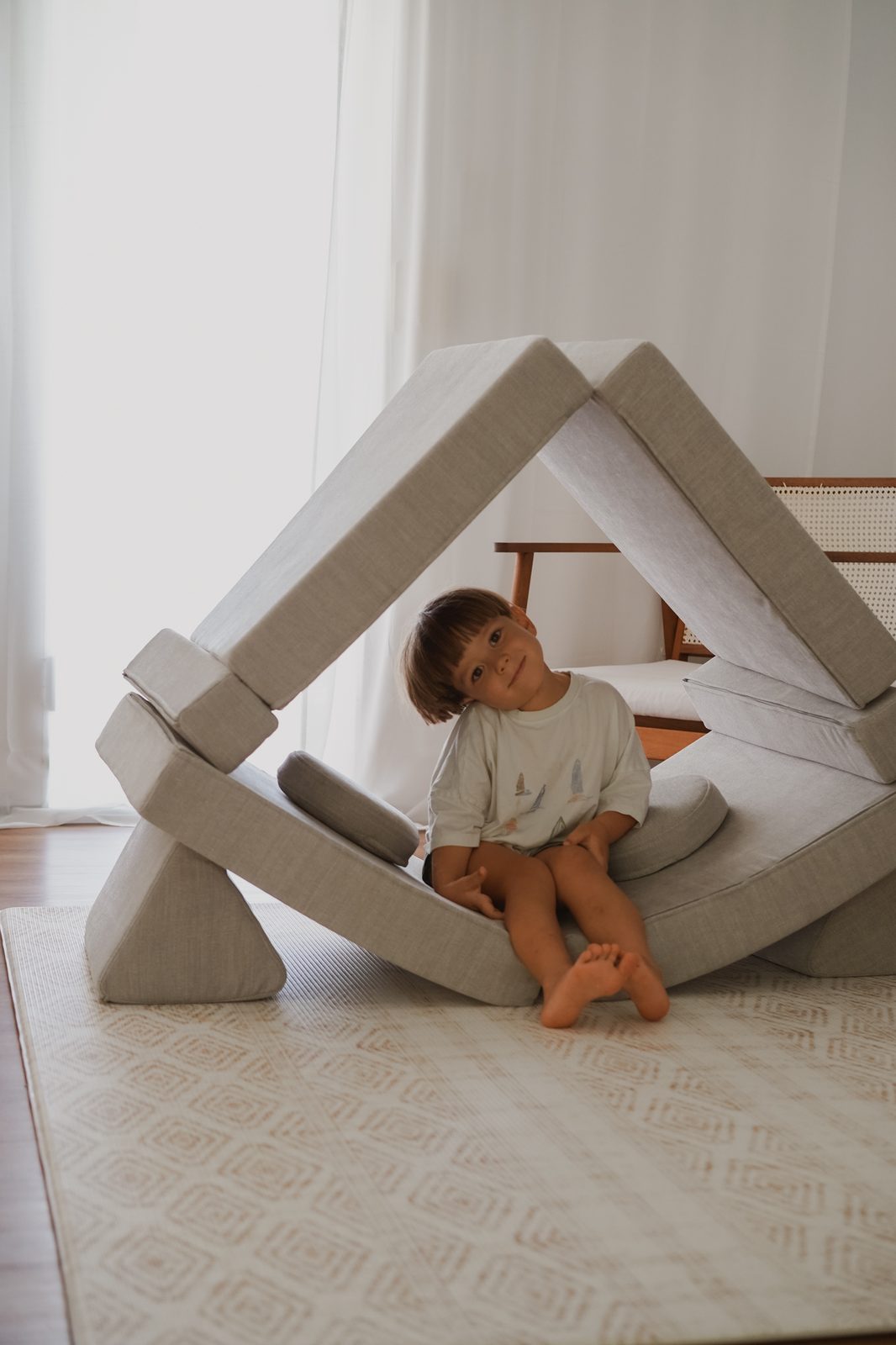 Boy sitting inside a fort made of triangular floor cushions