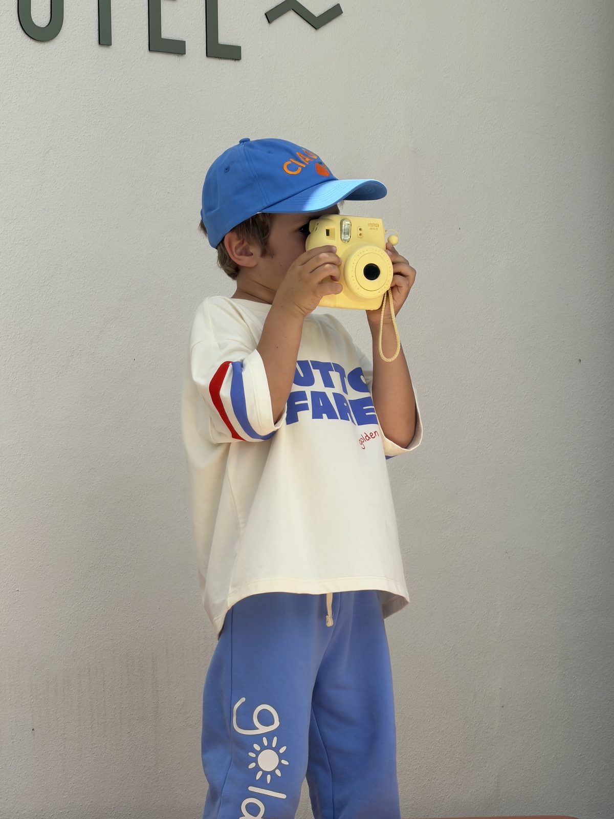 Boy in Golden brand outfit taking a photo with a yellow instant camera