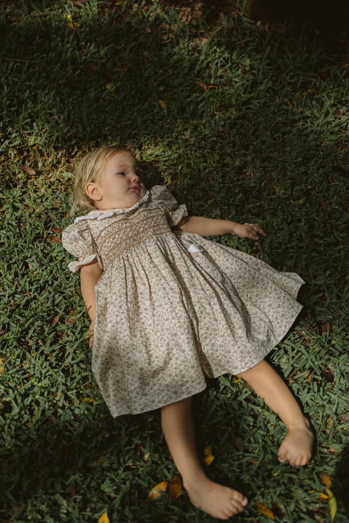 One of the kids, lying in the grass in a smocked dress