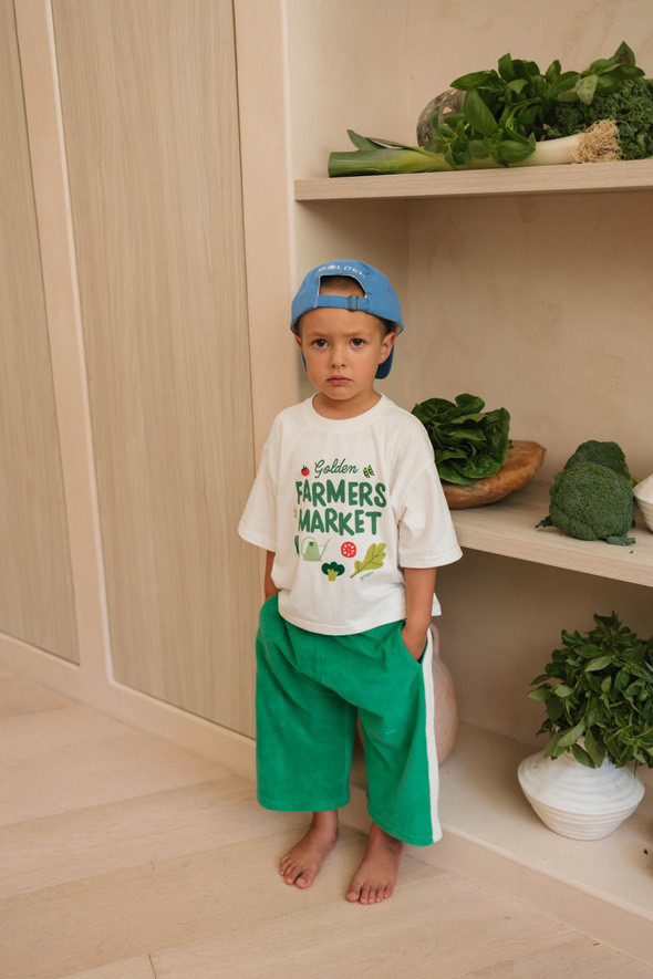 Young boy in a 'Golden Farmers Market' graphic tee and blue cap
