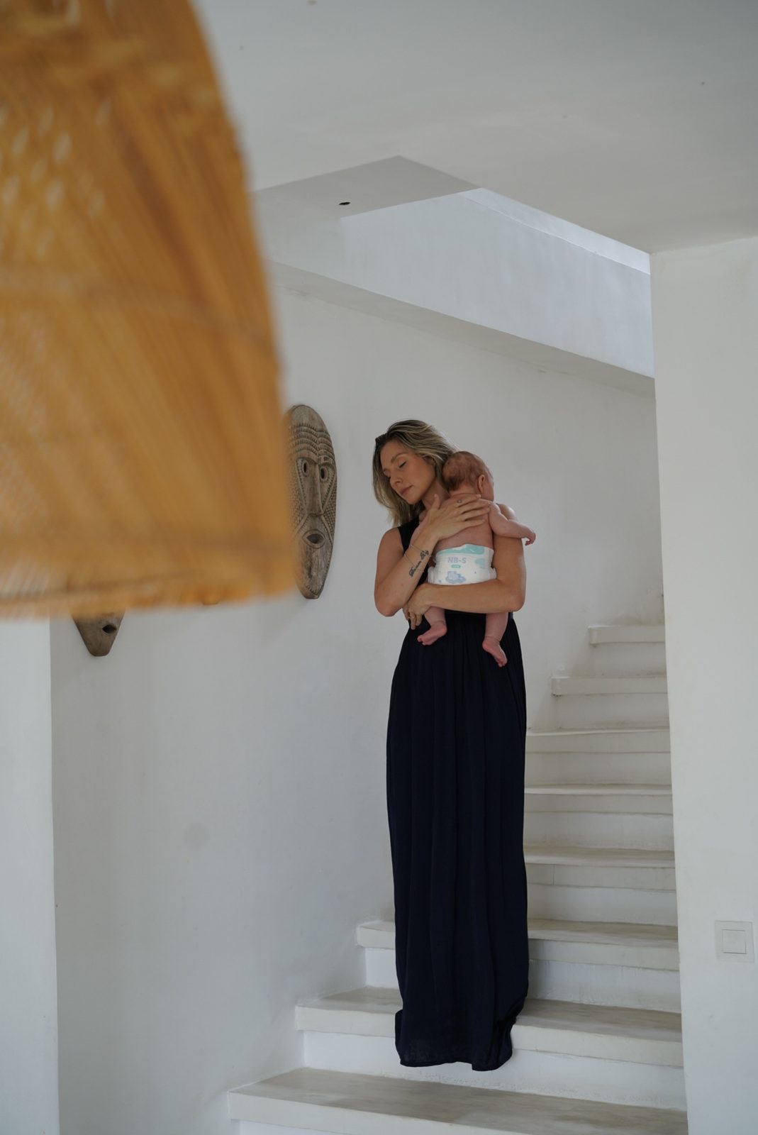 Mother carrying her newborn baby down a staircase