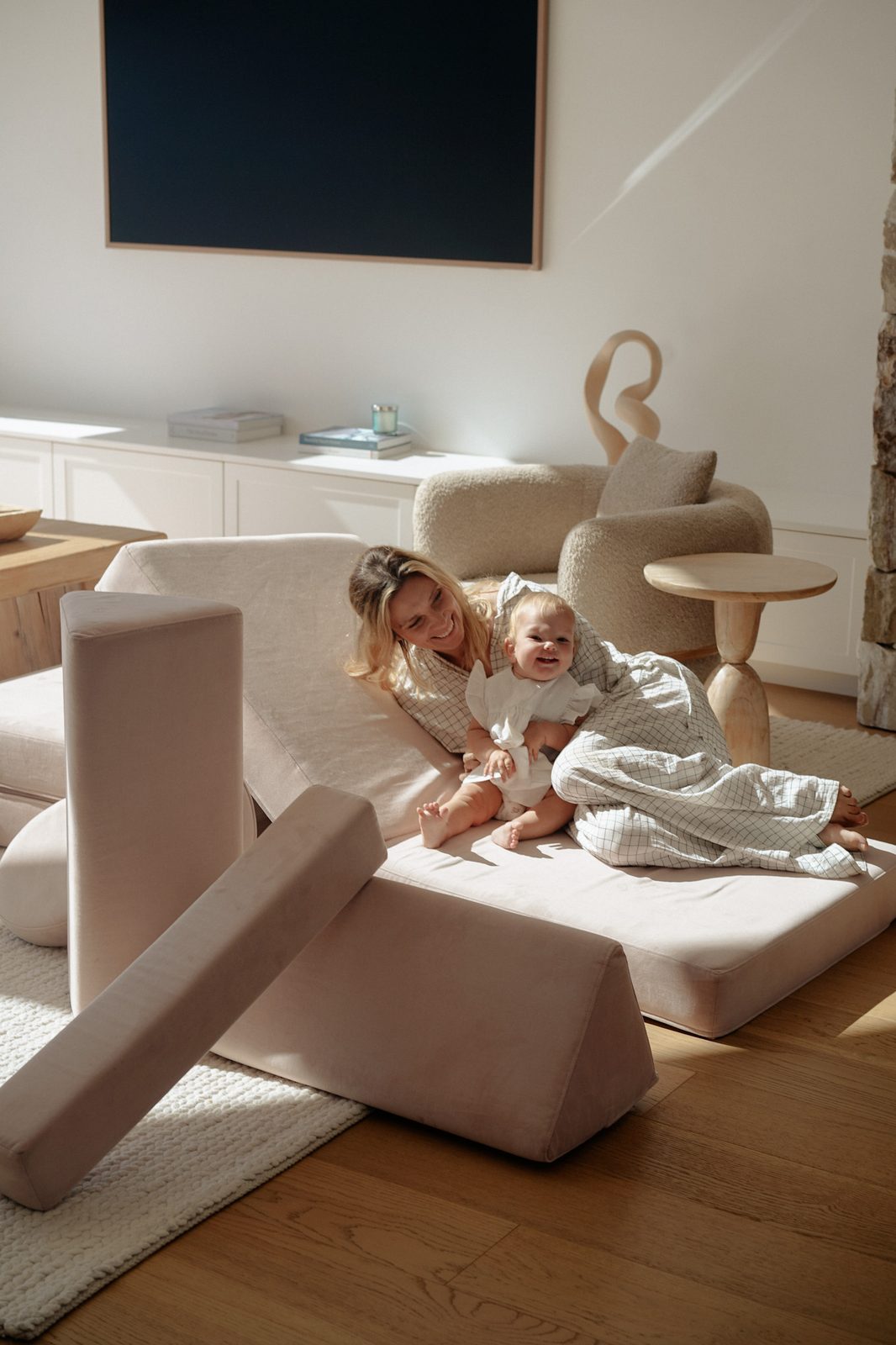 Mother and smiling baby wrapped in a checked blanket on a play couch