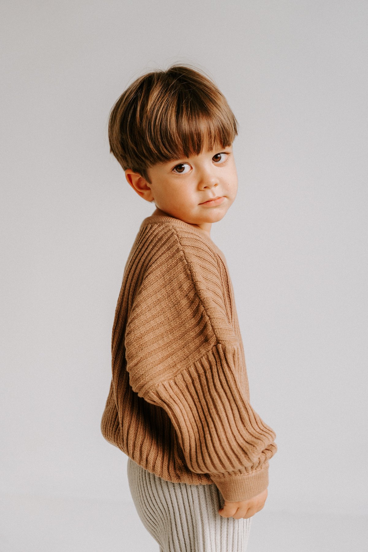 Kid in a knit sweater, side profile