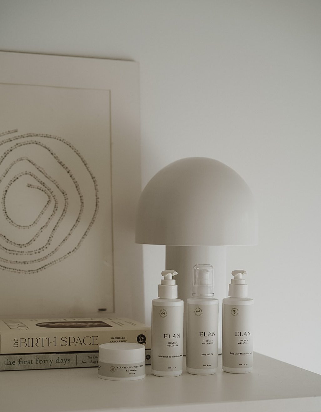 Elan House Wellness baby care product lineup styled beside parenting books