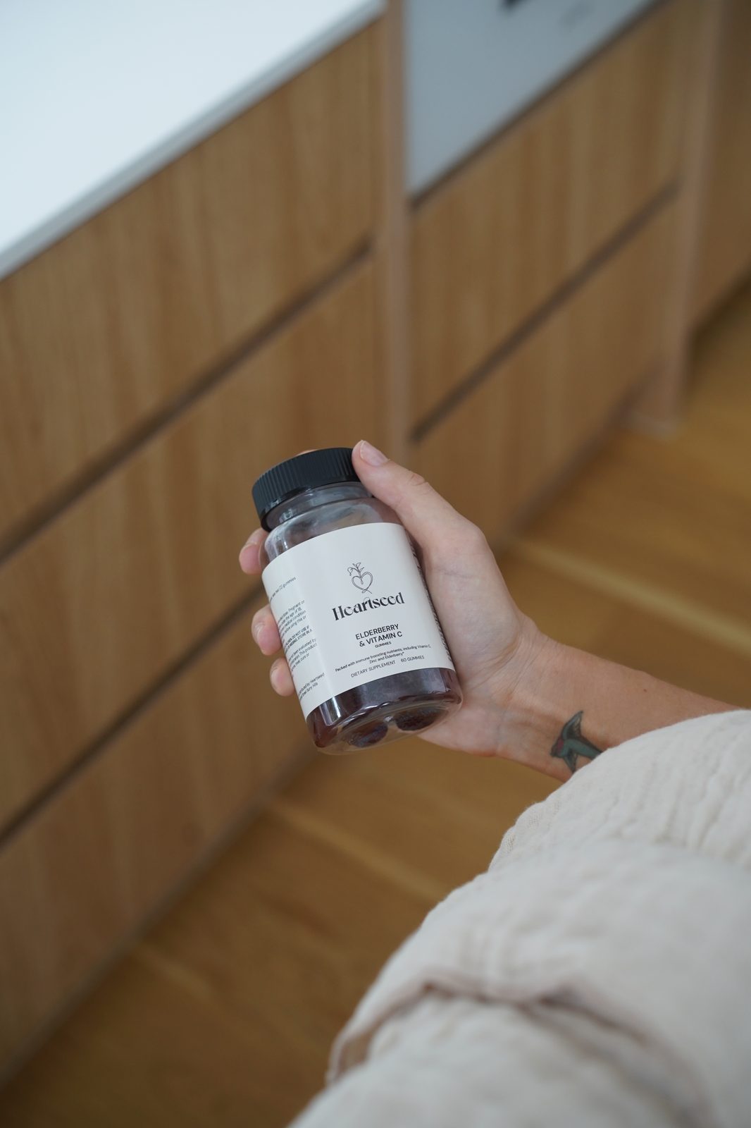 Hand holding a jar of Heartseed Elderberry & Vitamin C gummies