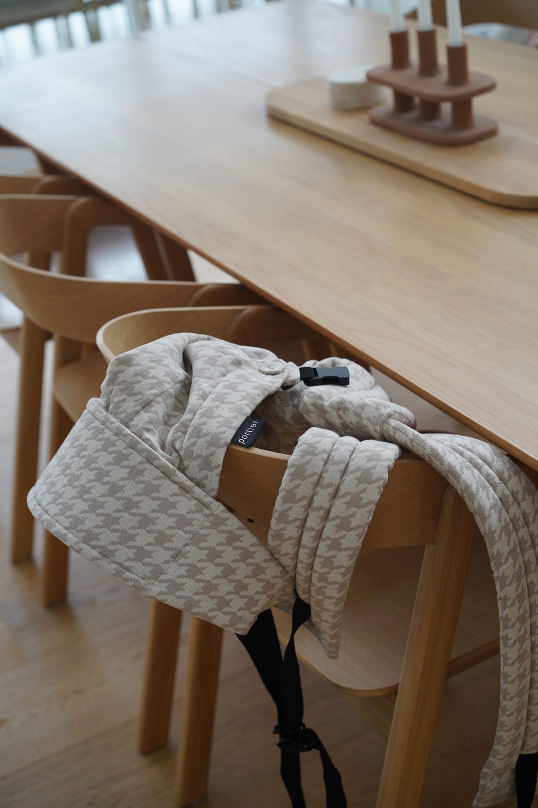 Houndstooth-patterned baby carrier draped over a dining chair