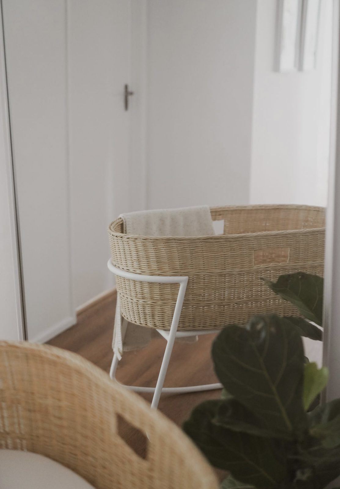 Woven wicker bassinet on a white stand styled in a nursery setting